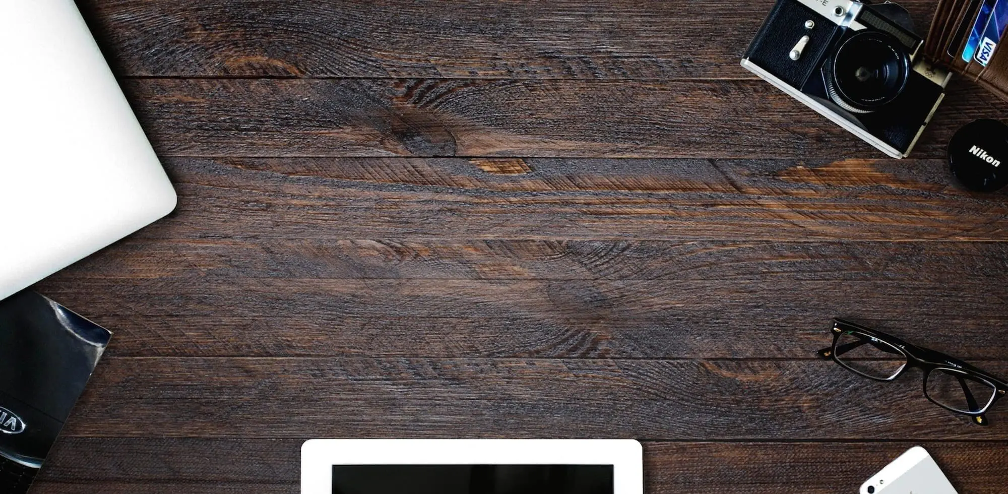 a flat lay image with laptop, camera, glasses