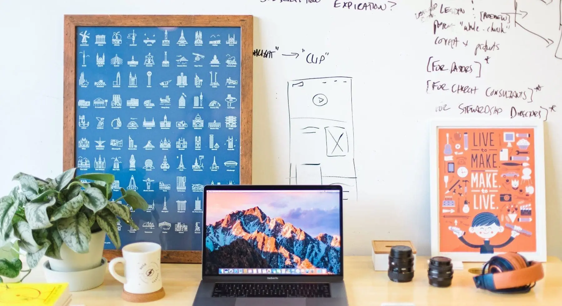 a workstation with laptop, plant, whiteboard