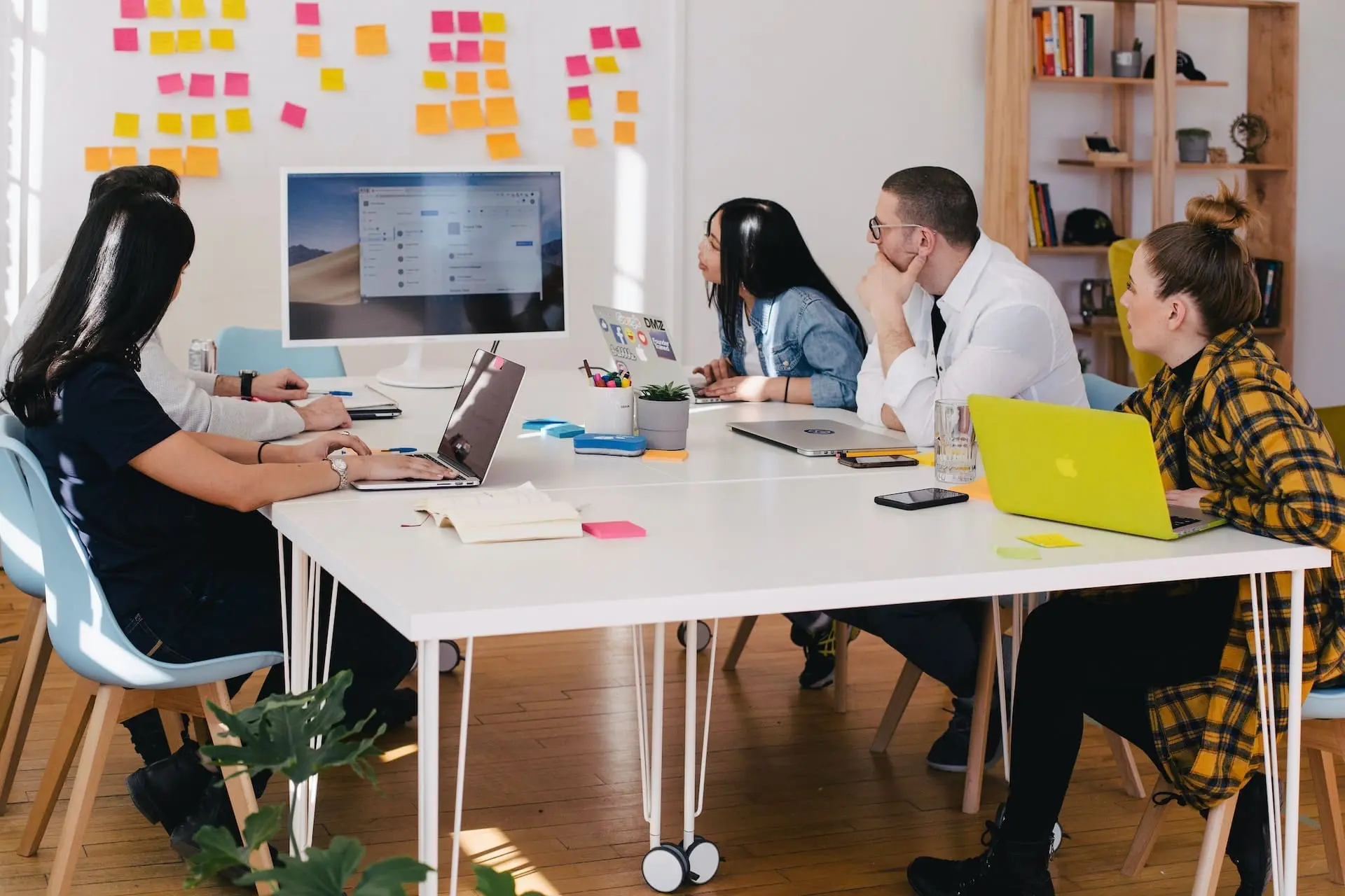 a group of people in a meeting looking on imac