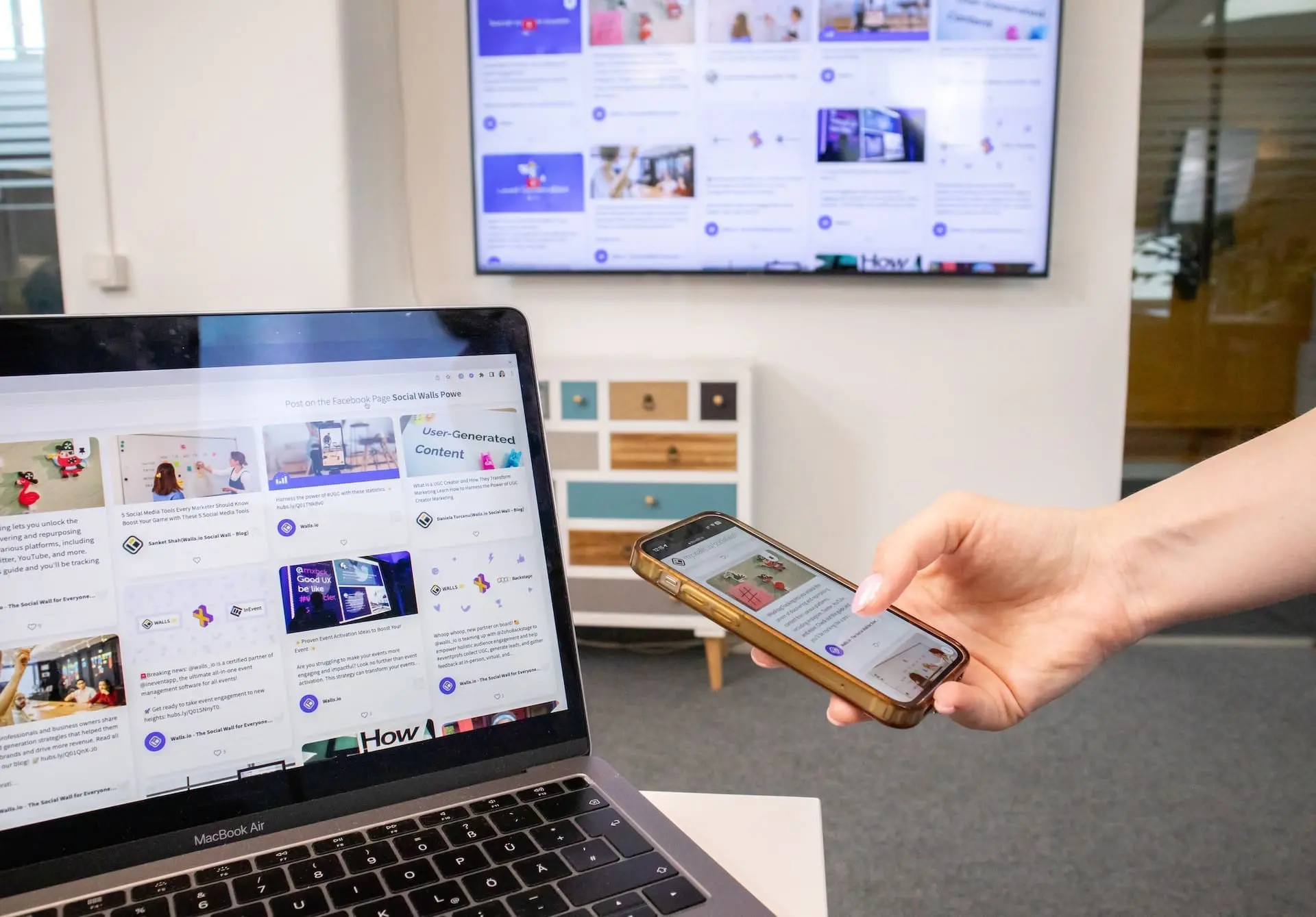 a person holding a mobile with laptop in background
