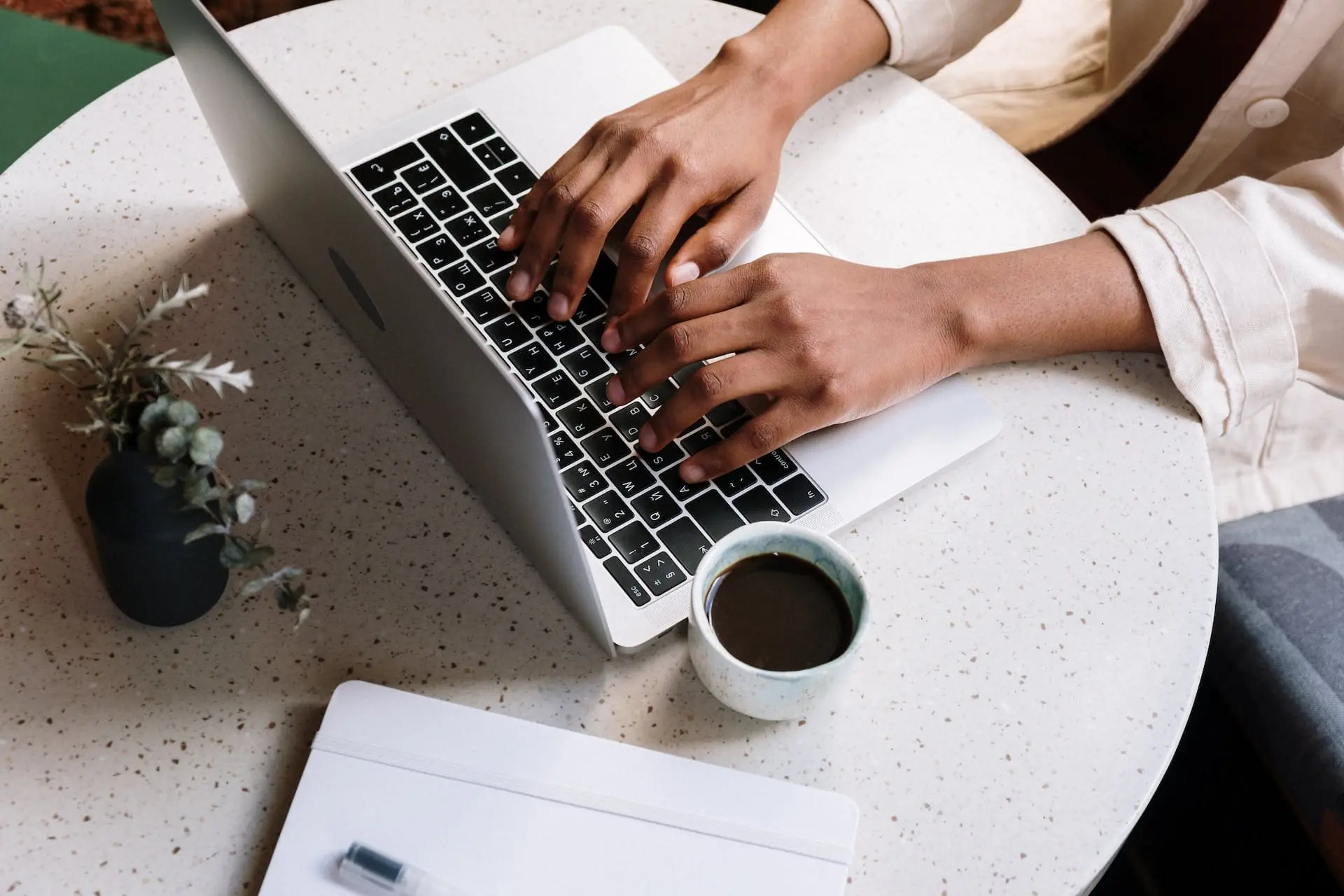 a person typing on a laptop with coffee