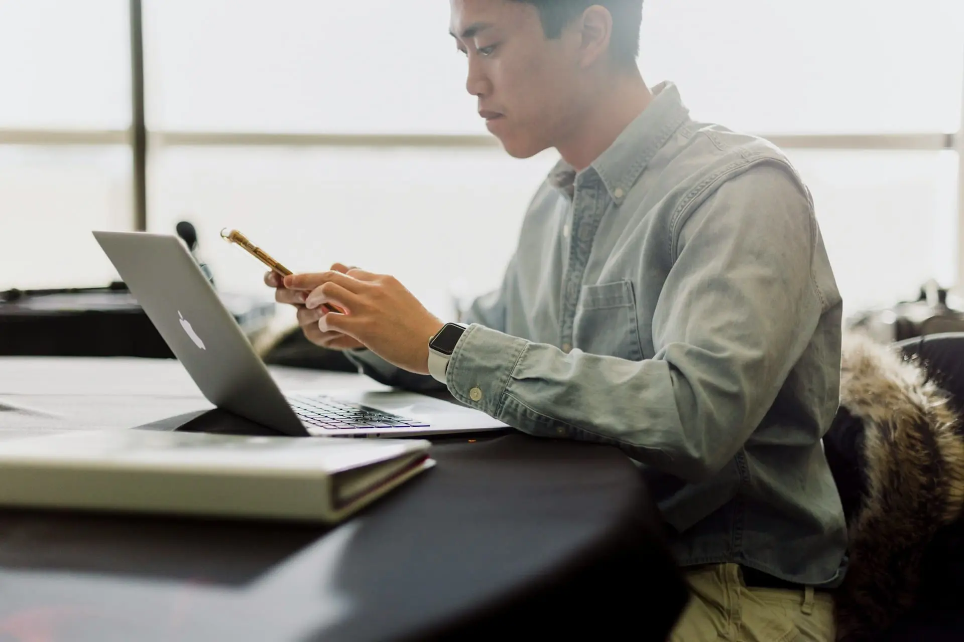 a man using a mobile phone in front of a laptop