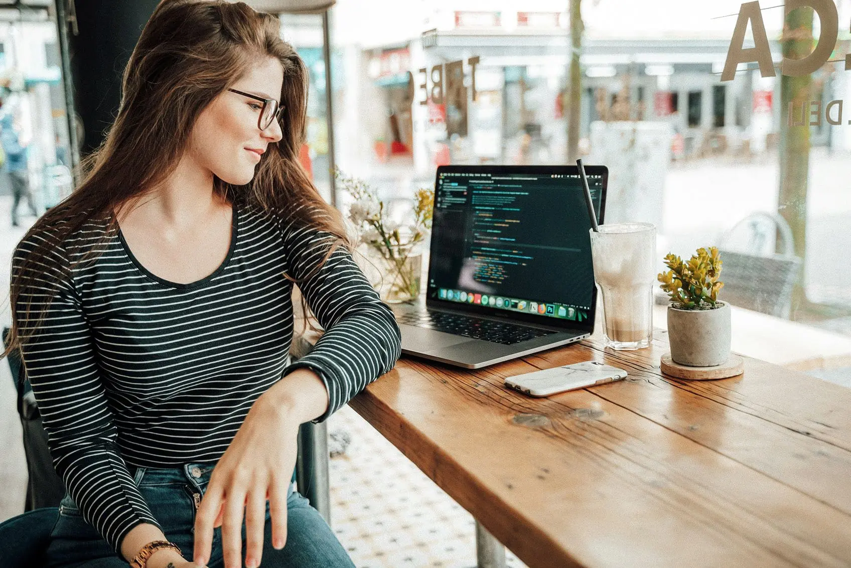 Woman coding on a computer in front of a cafe window - white label development